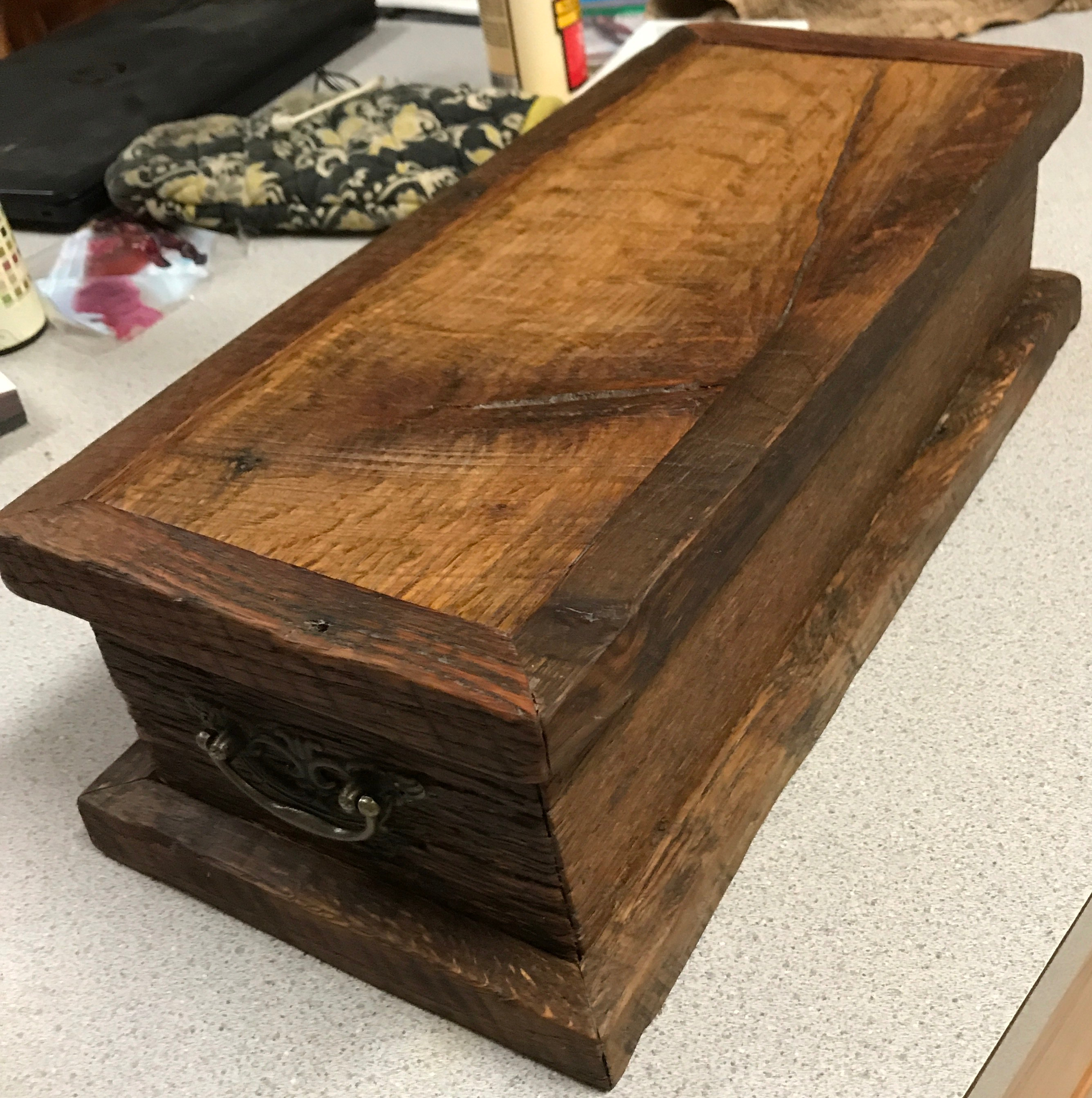 Solid barn wood oak box that is waxed with a light brown color and the mitered frame on the top and bottom is dark brown. Brass hanging handles on the box