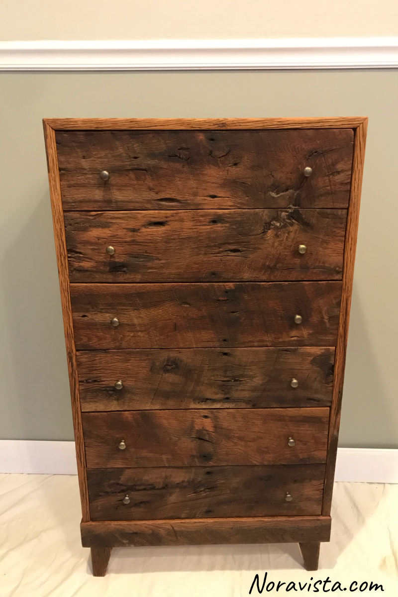 A midcentury Modern cabinet made from reclaimed oak barn wood featuring old nail holes, knots and saw tooth marks with the drawer fronts cut sequenced, and tiny brass knobs on the drawers for pulls