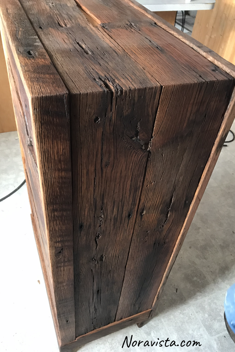 A midcentury modern waterfall cabinet side made from reclaimed oak barn wood featuring old nail holes