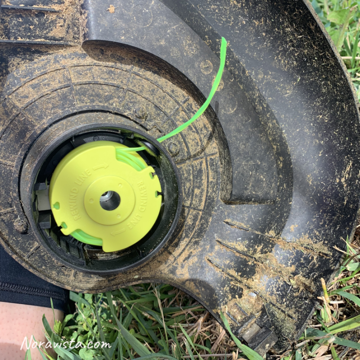 A Ryobi string trimmer with a new cartridge full of line installed on the end of the unit.